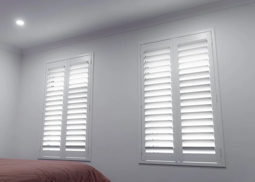 White walls with two windows fitted with white plantation shutters