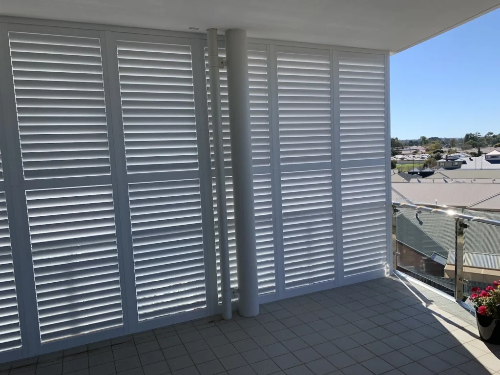 Aluminium plantation shutters enclosing a balcony with a suburban view