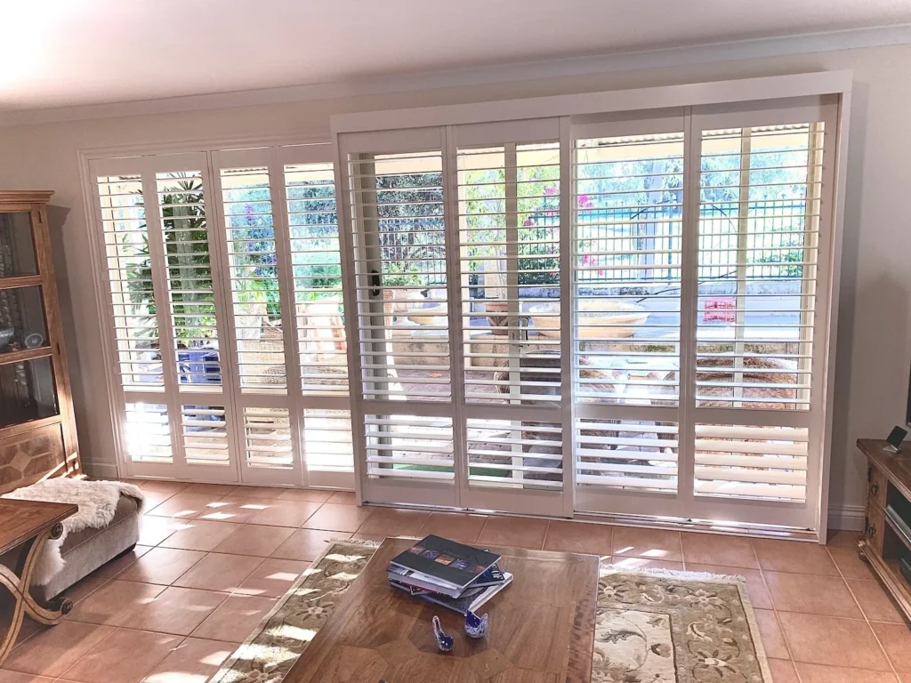 A row of white basswood plantation shutters across living room windows