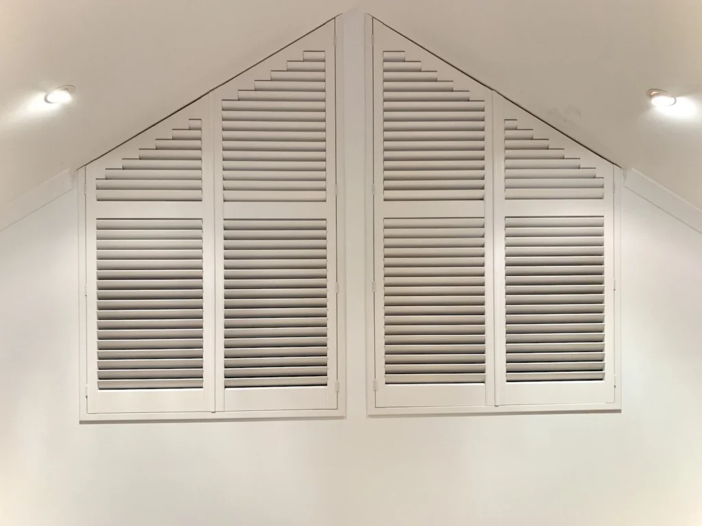 White basswood plantation shutters made to fit a triangular gable end window