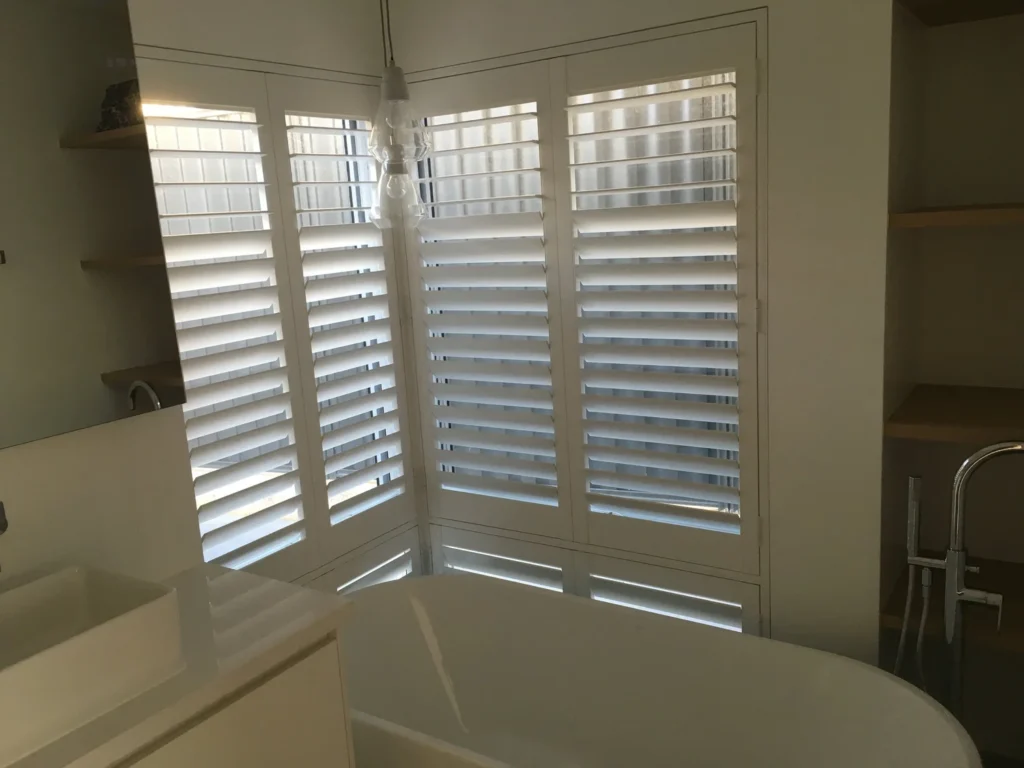 Plantation shutters above a bath with a horizontal T-post for clearance