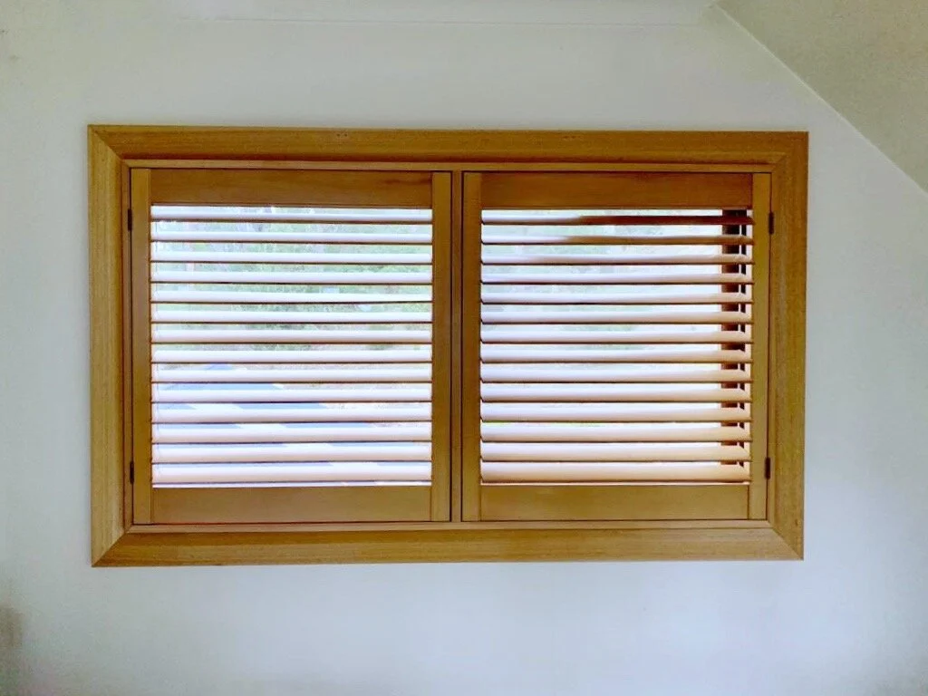 Timber plantation shutters in a natural stain on a bedroom window