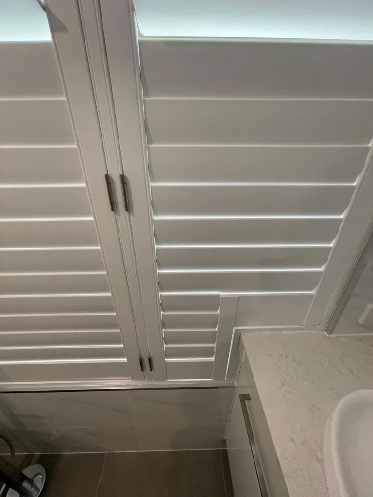 Moisture-resistant plantation shutters in a bathroom window