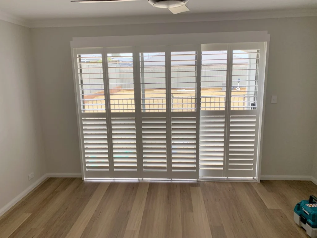White basswood plantation shutters across a wide window in a living room