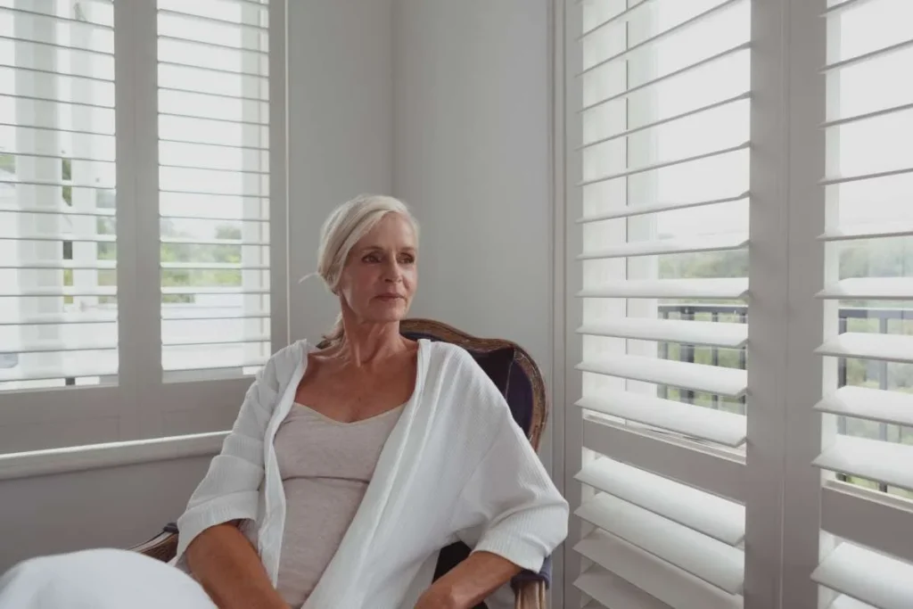 Woman sitting by a window with plantation shutters