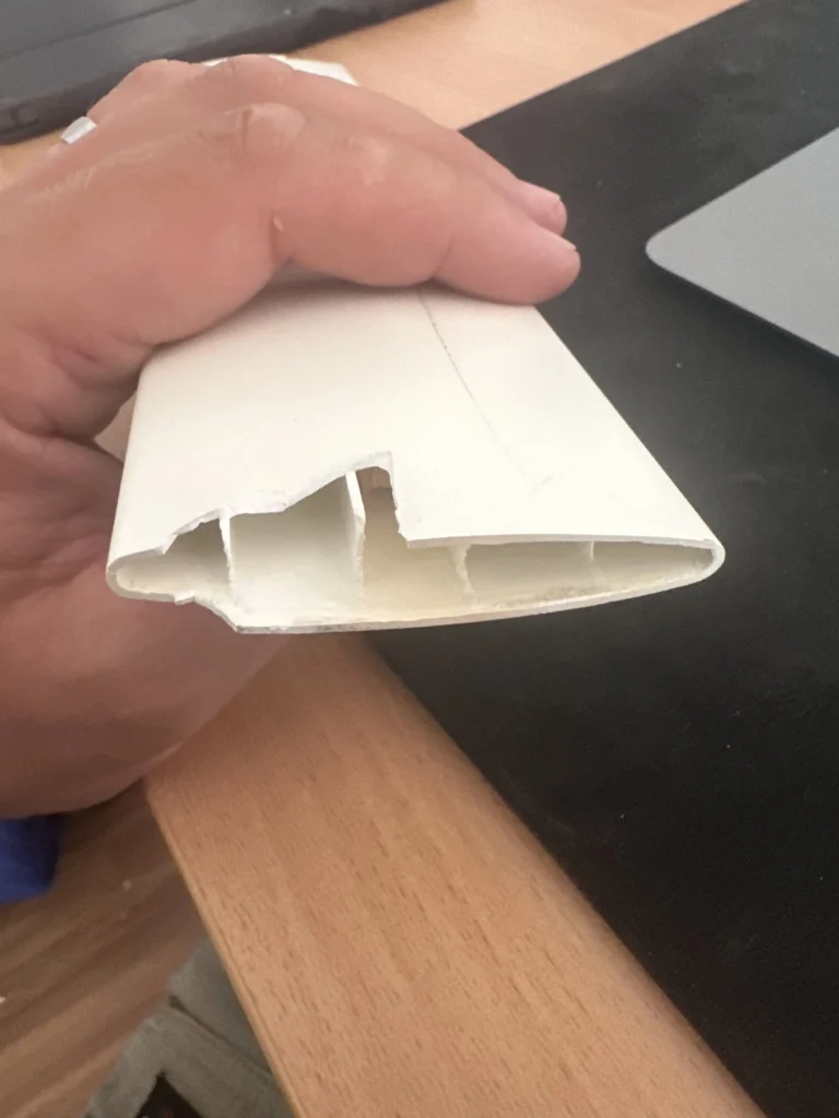 Hand holding a white PVC shutter frame part ready for a repair